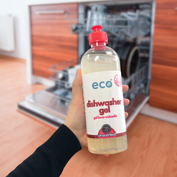 A bottle of eco dishwasher gel unscented held in front of a dishwasher, for an eco-friendly and sustainable home.